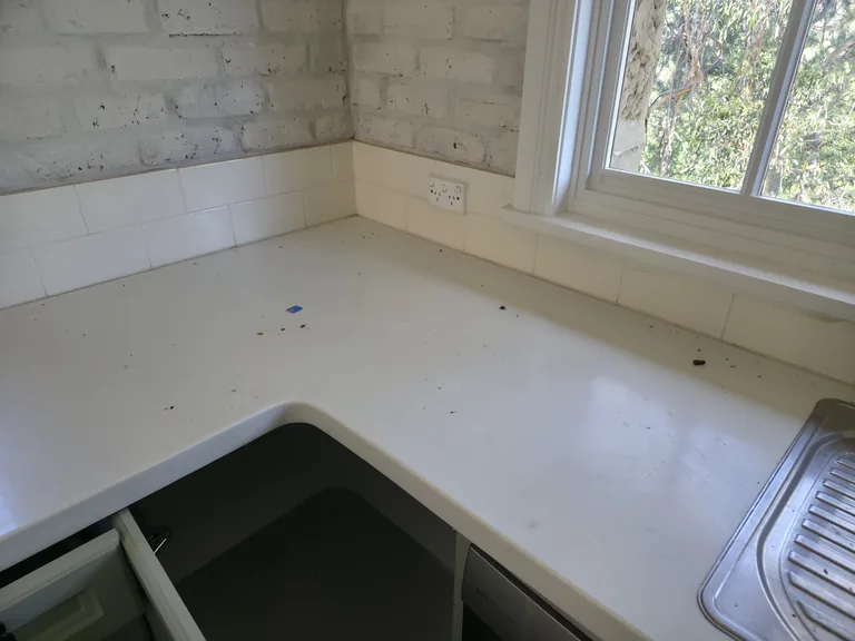 Debris and marks in the kitchen bench corner before cleaning