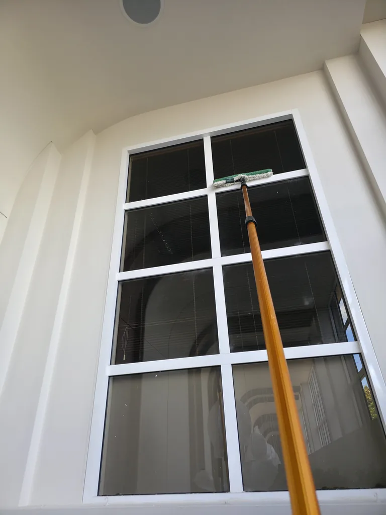 Extension-pole cleaning tool against the upper internal window frame