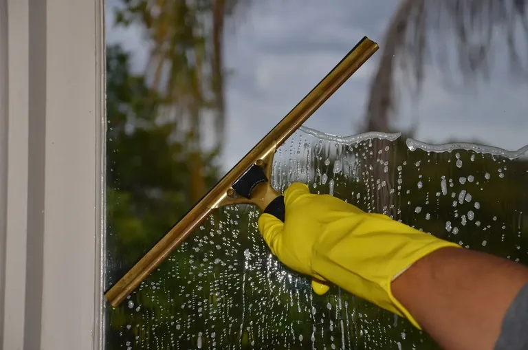 Cleaner using a squeegee on accessible exterior glass